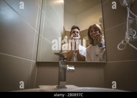 Morgens ein paar Routine. Mann und Frau teilen sich das Bad. Rasierbart und Zähne putzen Stockfoto