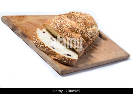 Geschnittenes Weißbrot mit Sesamsamen und Rosinen auf einem Küchenbrett. Hausgemachte Brote isoliert auf einem Weiß. Stockfoto