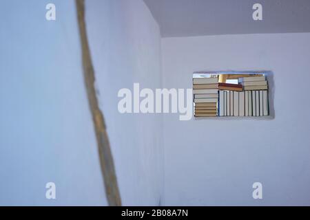 Satz Bücher, die innerhalb des Rechtecks in einer weißen Wand platziert werden, dunkel, offener Raum hell innen Stockfoto