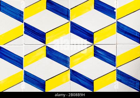 Portugiesische, traditionelle Fliesen Azulejos mit blauem und gelbem Geometriemuster auf weißem Hintergrund, das einen optischen Täuschungseffekt erzeugt. Stockfoto