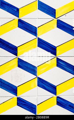Portugiesische, traditionelle Fliesen Azulejos mit blauem und gelbem Geometriemuster auf weißem Hintergrund, das einen optischen Täuschungseffekt erzeugt. Stockfoto