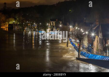 Ironbridge, Großbritannien. Februar 2020. Die Hochwasserschutzanlagen entlang der Wharfage in Ironbridge schafften es, den 470 Tonnen pro Sekunde Wasser zu widerstehen, das durch das Weltnaturerbe der Ironbridge Gorge fließt, als der River Severn seinen Höhepunkt in den frühen Morgenstunden des Dienstag, den 18. Februar 2020 erreichte. Die lange Exposition erzeugt einen Millldeich-Effekt auf die wütende Torrent der wirbelnden Eddies, die bereits zahlreiche Anwesen entlang des Flusses Severn in Shropshire überschwemmt hatten. Credit: Paul Bunch/Alamy Live News. Stockfoto