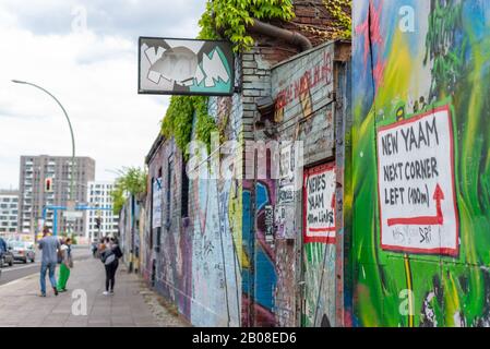 Berlin, Friedrichshain. Referenzen zu YAAM, Young African Art Market mit Wand in bunter Straßenkunst Stockfoto