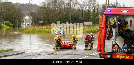 NANTGARW, IN DER NÄHE VON CARDIFF, WALES - FEBRUAR 2020: Feuerwehrleute, die eine ältere Dame nach der Evakuierung aufgrund von Überschwemmungen in Nantgarw auf einem aufblasbaren Boot tragen. Stockfoto
