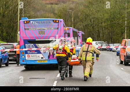 NANTGARW, IN DER NÄHE VON CARDIFF, WALES - FEBRUAR 2020: Feuerwehrleute, die eine ältere Dame auf einer Bahre nach der Evakuierung wegen Überschwemmungen in Nantgarw tragen Stockfoto