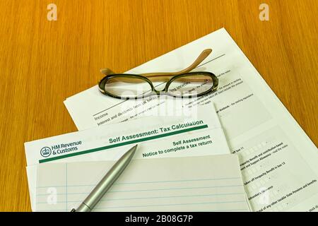 Großbritannien - FEBRUAR 2020: Formular zur Selbsteinschätzung von HM Revenue & Customs auf einem Holztisch mit Stift und Brille Stockfoto