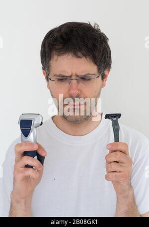 Mann mit Bart unentschieden, ob man zum Schneiden von Bart elektrischen Rasierer oder Rasiermesser verwendet. Stockfoto