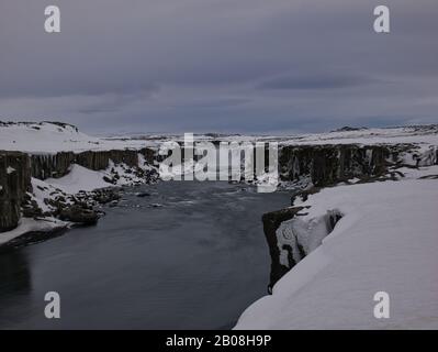 Eine lange Zeit andauende Exposition des Dettifoss Wasserfalls mit Schnee Stockfoto