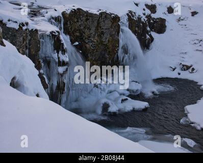 Der Wasserfall Kirkjufellsfoss in Island ist von Schnee und Eis umgeben Stockfoto