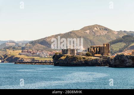 Castro Urdiales, Spanien. Blick auf Santa Maria de la Asunción Kirche und Burg von Santa Ana Leuchtturm aus dem Cementerio de Ballena Stockfoto