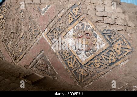 Bemalte und geschnitzte Reliefe des gottes Ayapec aus der präinkanisch-mochicanischen Kultur an den adobe-wänden der Huaca de la Luna bei Trujillo, Peru Stockfoto