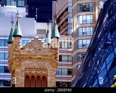 Toronto Architekturfoto. Steinerner Kirchturm in der Innenstadt von Toronto mit modernen hohen Glas-Bürotürmen im Hintergrund: Die Roy Thomson Concert Hall Stockfoto