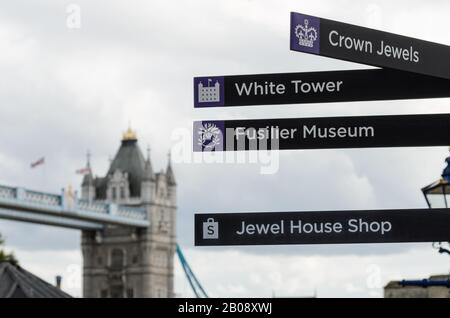 Ein Schild auf dem Gelände des Tower of London mit Tower Bridge im Hintergrund, in London, England. Stockfoto