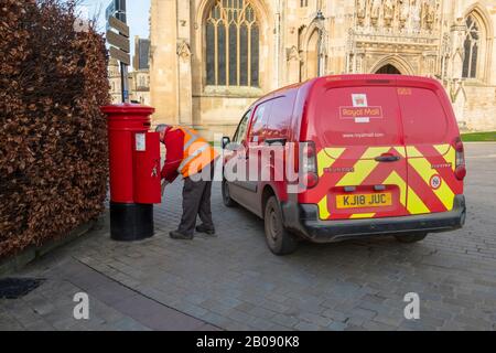 Ein Postmann leert einen Postkasten vor der Kathedrale von Gloucester. Stockfoto