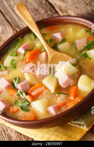 Pfausuppe mit Gemüse und Schinken in einer Schüssel auf dem Tisch aufteilen. Vertikal Stockfoto