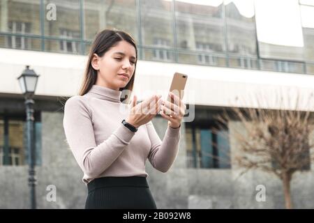 Attraktive Geschäftsfrau hält Handy auf der Suche nach Informationen im Internet Stockfoto