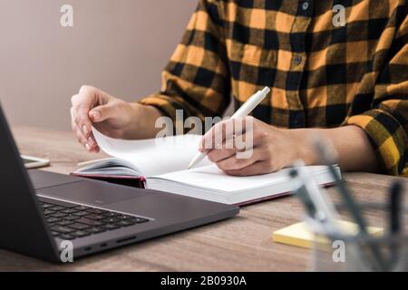 Nahaufnahme der Hände einer Geschäftsfrau, Student in gelbem Hemd macht Notizen Stockfoto