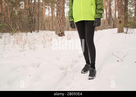 Nahaufnahme einer nicht erkennbaren Frau in Sportschuhen Wandern im Winterwald Stockfoto