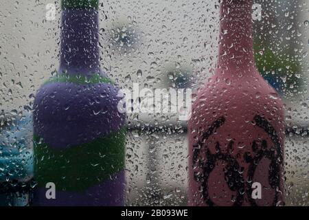 Am Frühlingnachmittag fällt Regen auf das Glas. Nahaufnahme eines Fensters mit herabfallenden Regenfällen.Der Regen fällt auf die Haushaltsfenster. Konzentrieren Sie sich auf Regen Stockfoto