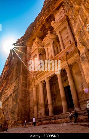 Petra, JORDANIEN - 30. JANUAR 2020: Touristen genießen sonnigen Tag im berühmten Tempel El-Khazneh, in Felsen gehauen Petra Komplex und Touristenattraktion, Haschemite Königreich Jordanien, Sonneneinstrahlung Beugung Stockfoto