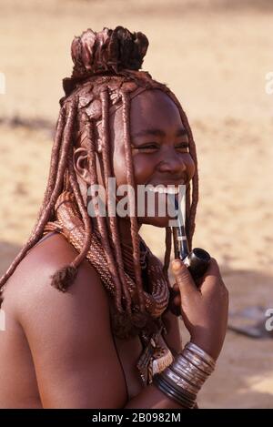 AN DER SKELETTKÜSTE, IM TAL VON HARTMANN, IM NOMADISCHEN LAGER DER MENSCHEN IN HIMBA, IN DER HIMBA FRAU MIT PFEIFE Stockfoto