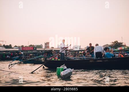 Ein vietnamesischer Mann auf seinem Boot bei Sonnenaufgang mit Blick auf den schwimmenden Markt in Can Tho, Vietnam. Stockfoto