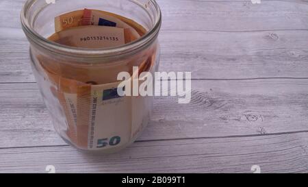 Sparkonzept, Euro-Banknoten im Glasbecher auf Holztisch Stockfoto