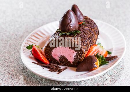 Nahaufnahme einer Schokoladenkuchenrolle mit frischer Erdbeermaus und mit schokoladenüberzogenen Erdbeeren garniert Stockfoto
