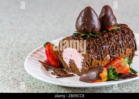 Nahaufnahme einer Schokoladenkuchenrolle mit frischer Erdbeermaus und mit schokoladenüberzogenen Erdbeeren garniert Stockfoto