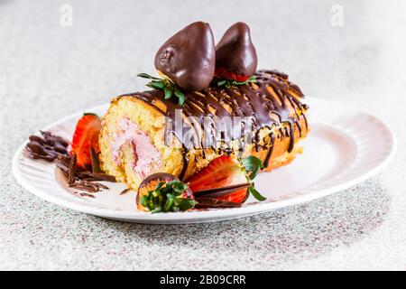 Nahaufnahme einer Vanillekuchenrolle mit frischer Erdbeermaus und mit schokoladenüberzogenen Erdbeeren garniert Stockfoto