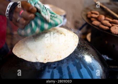 Der Mann, der ein lta tawa Paratha Brot auf einem hochgedrehten Topf mughal-küche aus indien und pakistan zubereitet Stockfoto