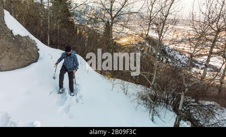 Wanderer in den Bergen spazieren mit Schneeschuhen. Ein Mann steigt an die Spitze. Winterbergtourismus. Kasachstan Stockfoto