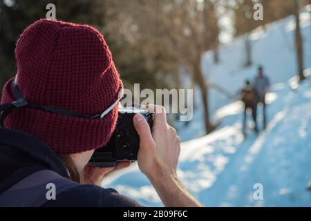 Der Kerl schießt im Winter ein Foto von Reisenden. Rückansicht. Nahaufnahme Stockfoto