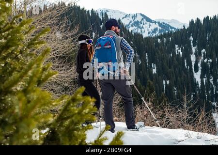 Der Kerl mit dem Mädchen im Winter in den Bergen. Wintertourismus im Freien mit Schneeschuhen. Berge Tien Shan. Kasachstan Stockfoto