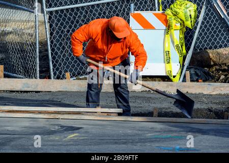 Betonbauunternehmer, der einen Gehweg, eine Bordsteinkante und eine Sturmabflussrinne auf einer neuen Hauskonstruktion installiert. Stockfoto