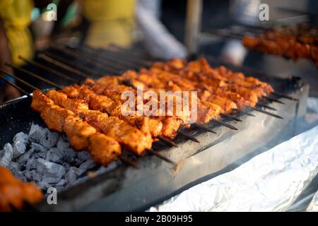 Paneer Fischhuhn Tikka brüten auf einem offenen Herd mit glühenden Kohlen und Rauch aus Stockfoto