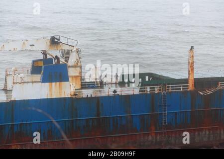 Cork, Irland. Feb. 2020. Atlas Cargo Ship, Ballyanna, Cork City EIN Mann, der sich den steilen Hang hinunter zum Boden machte und den provisorischen lader auf das Deck klimte. Atlas-Cargo-Schiff an der Küste von Ballycotton, östlich von Ballyanna, aufgespült. Viele Zuschauer machten sich auf den Weg durch Felder und steile Hänge, um das Wrack selbst zu sehen, einige kamen sogar zu einem genaueren Blick, stiegen die provisorische Leiter hinauf und erkundeten das Schiffsdeck trotz starker Winde und Regen. Credit: Damian Coleman/Alamy Live News Stockfoto