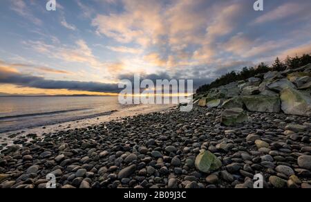 Schöner dynamischer Sonnenaufgang über der Küste mit dramatischen Wolken über dem felsigen Strand auf Vancouver Island, British Columbia, Kanada Stockfoto