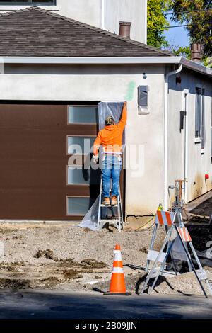 Bauarbeiter legen Klebeband auf eine Tür, um sie zu schützen, bevor sie an der Wand mit Stuck putzen. Renovierungshauskonzept. Stockfoto