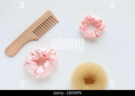 Haarbürste aus Holz, Barrette und Pink Scrunchy isoliert auf Weiß. Flat Lay Frisierwerkzeuge und Accessoires Color Hair Scrunchies, Elastisches Haar Stockfoto