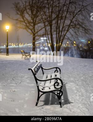 Budapest, Ungarn - Zwei Bänke und Lampenpfosten in einem verschneiten Park im Buda-Viertel mit Szechenyi-Kettenbrücke im Hintergrund bei starkem Schneetreiben in Winte Stockfoto