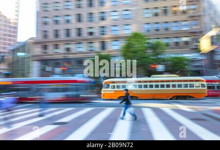 Kameraschwenkung der Fußgänger am Crosswalk und fahrende Trolleybusse im Hintergrund auf Der Market Street in San Francisco, Vereinigte Staaten. Stockfoto