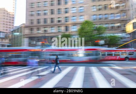 Kameraschwenkung der Fußgänger am Crosswalk und fahrende Trolleybusse im Hintergrund auf Der Market Street in San Francisco, Vereinigte Staaten. Stockfoto