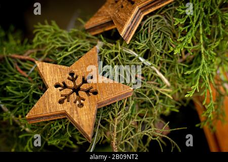 Grüner Weihnachtskranz, der an einer Holztür mit Fensterglas hängt und mit Holzsternen verziert ist Stockfoto