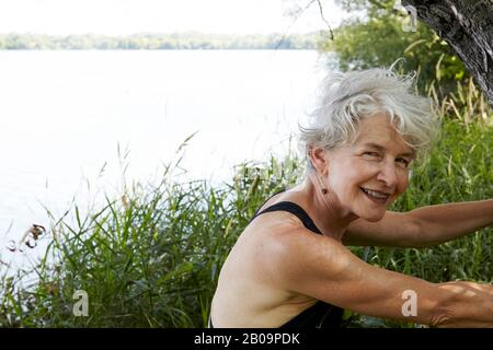 Schöne 65-jährige Frau schwimmend im See Stockfoto