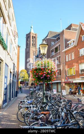 Venlo, Limburg-Niederlande - 13. Oktober 2018: Einkaufsstraße im historischen Zentrum der niederländischen Stadt. Im Vordergrund geparkte Fahrräder. Menschen, die auf der Straße spazieren. Turm im Hintergrund. Stockfoto