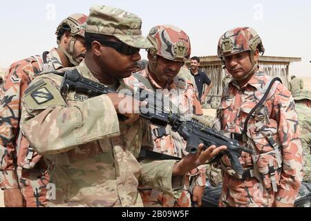 Spc der US-Armee. Reginald Cheeseboro vom 155. Armed Brigade Combat Team, links, zeigt omanischen Soldaten seine M4-Karbine in einer Waffenreichweite vom 20. Januar 2019 in Thumrait, Oman. Stockfoto