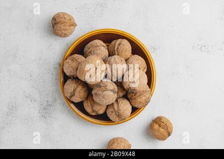 Walnüsse in runder Platte auf hell strukturierter Oberfläche. Gesunde Nüsse, gesunde Lebensmittel. Stockfoto