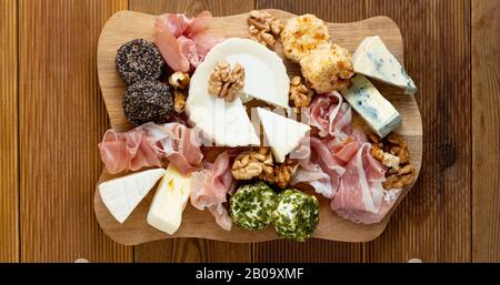 Verschiedene Käsesorten, Trauben, Walnüsse, Honig und Prosciutto. Holzschneidplatte. Stockfoto