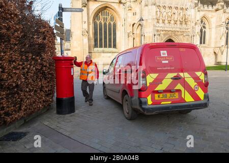 Ein Postmann bereitet sich darauf vor, einen Postkasten vor der Kathedrale von Gloucester zu leeren. Stockfoto